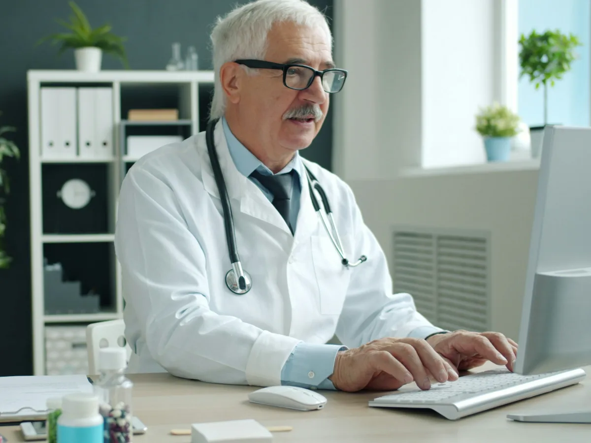 Clinician typing a visit note at a computer in a clinic office